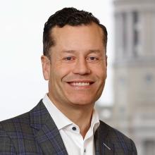 David smiling, wearing a grey suit jacket and white button up shirt