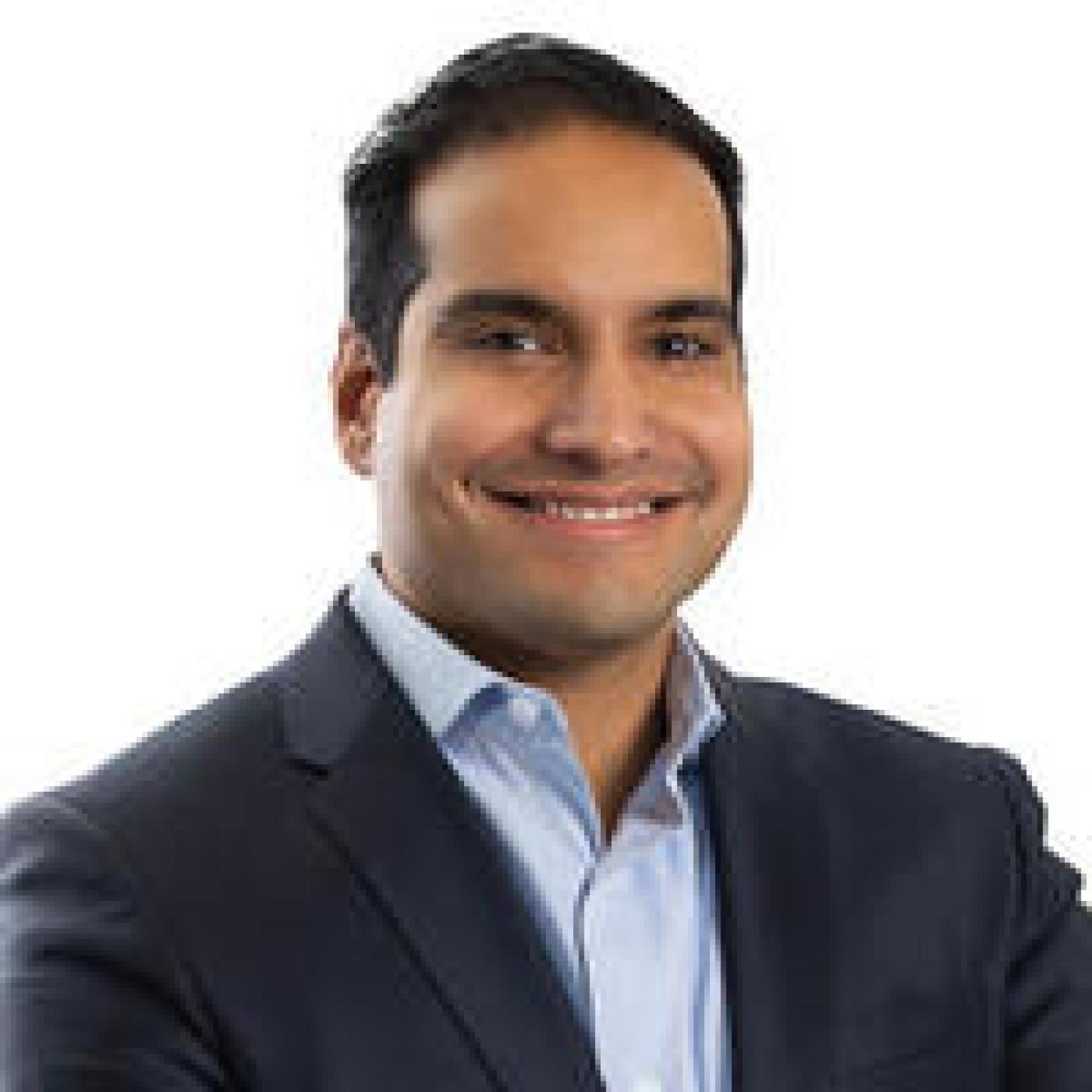 Man wearing gray suit and blue shirt looking at camera