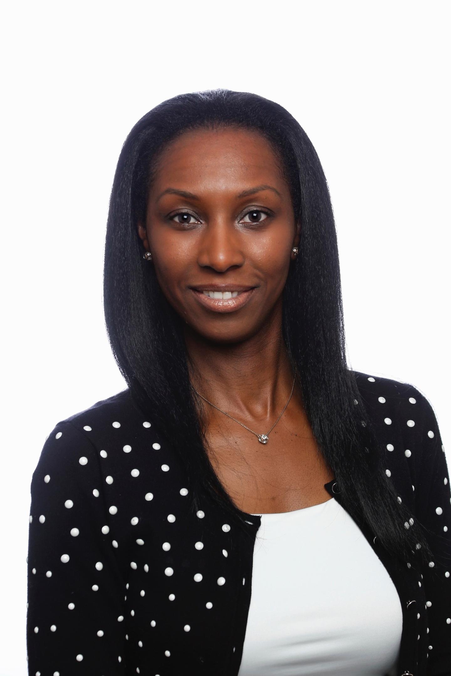 A picture of panelist, Iris Hosea. She's smiling and wearing a black and white polka dot cardigan with a white undershirt.