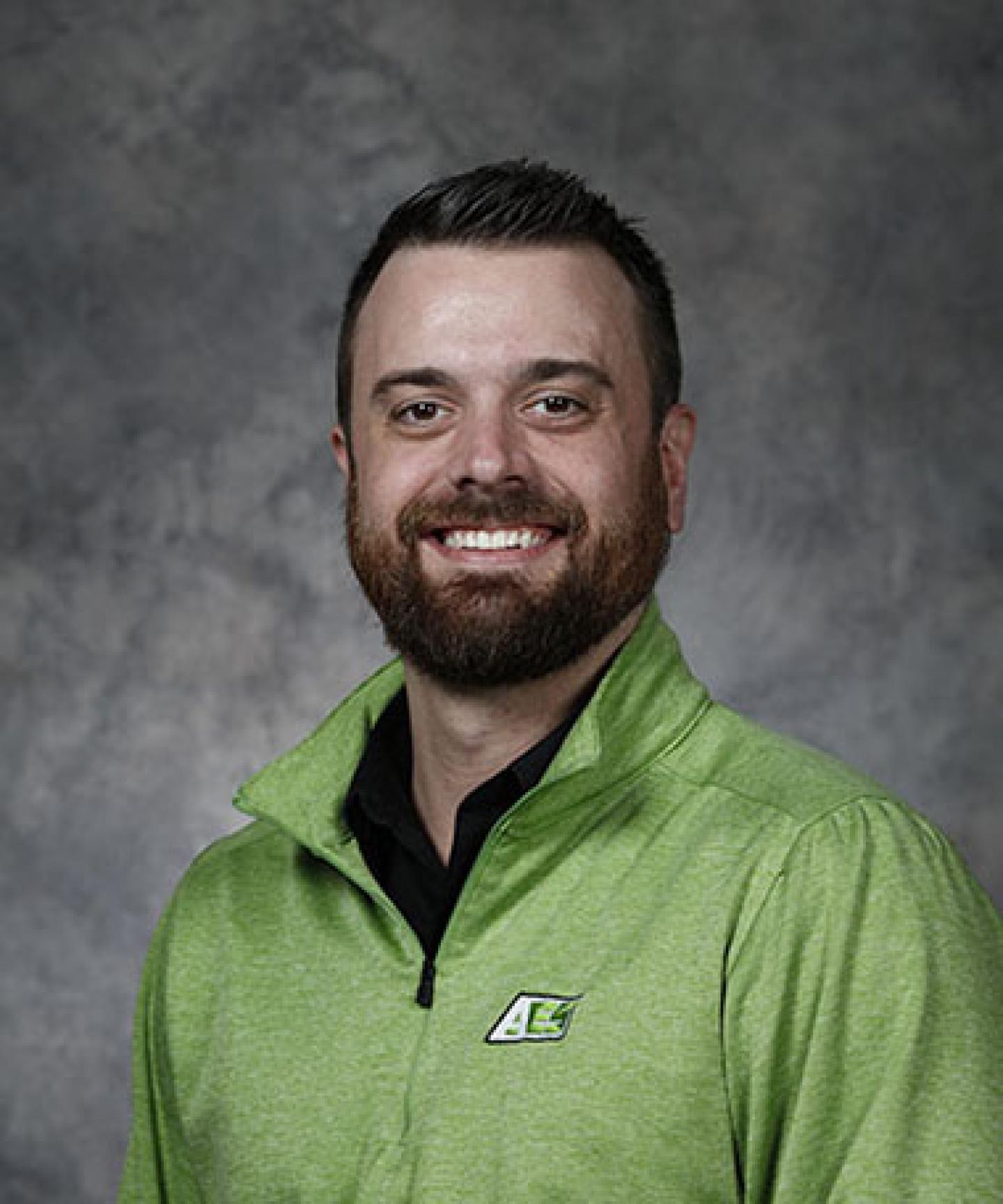 smiling bearded man in green company polo