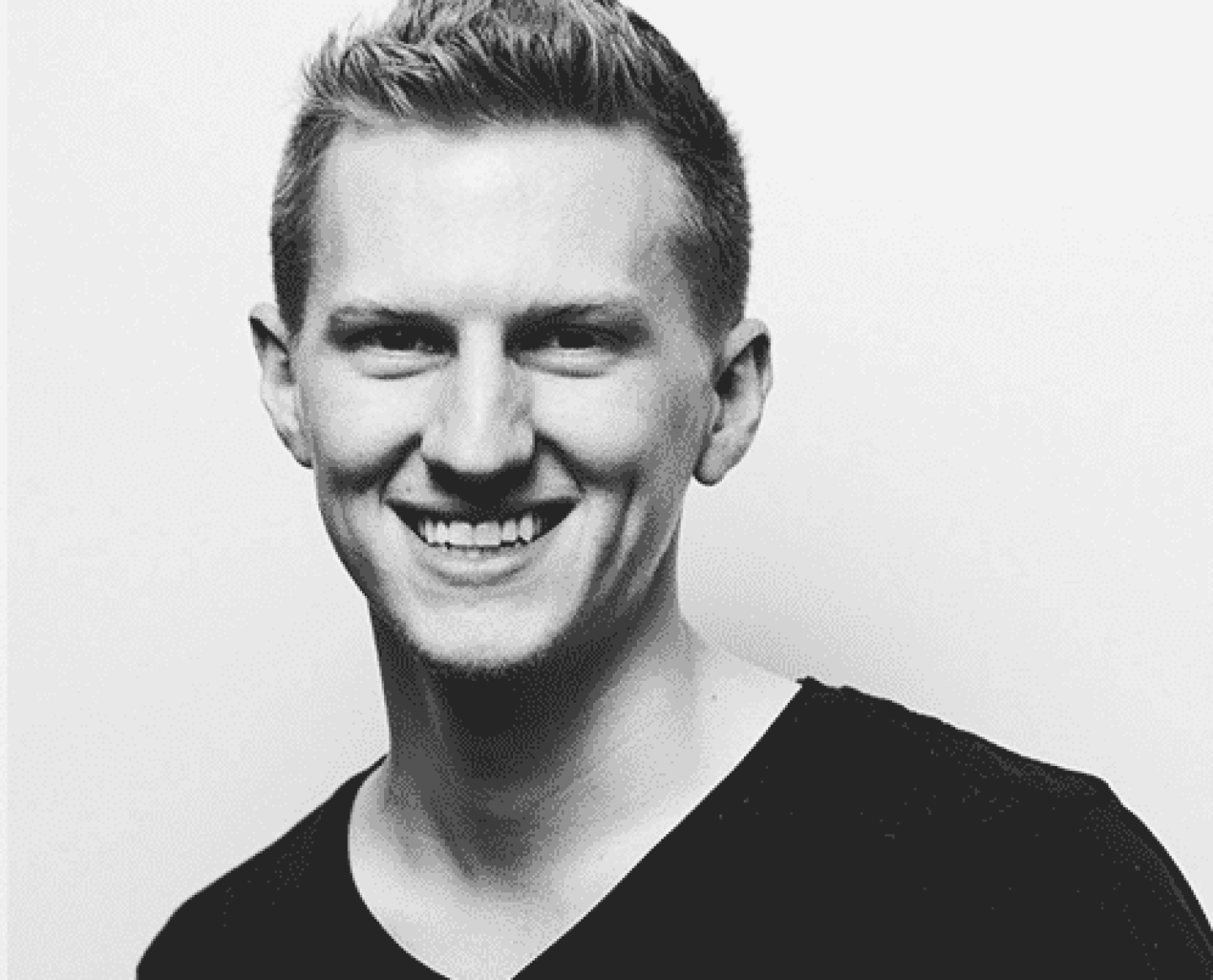 black and white photo of a young man smiling, wearing a black tee shirt