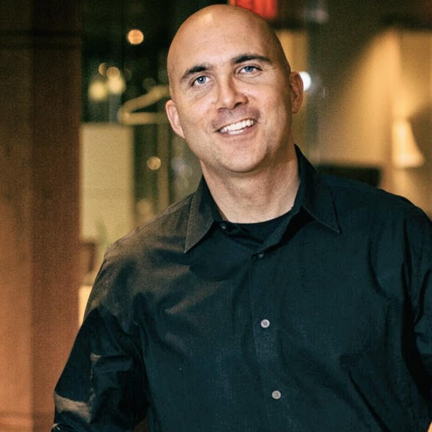 smiling man in a black button down tee shirt