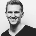 black and white photo of a young man smiling, wearing a black tee shirt